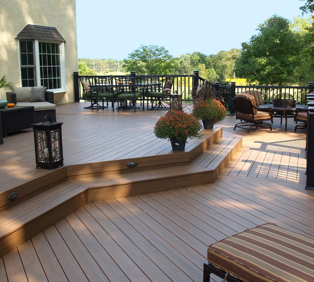 Deck with step up with furniture and plants.