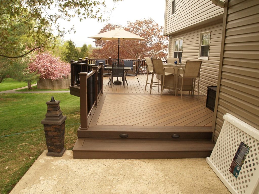 McHenry step up to a deck with a hightop table and low table with an umbrella.