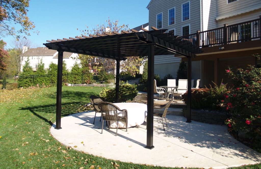 Pergola in a Backyard With Table and Chairs Under